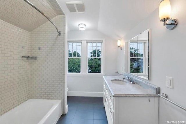 bathroom with tile patterned flooring, vanity, tiled shower / bath, and vaulted ceiling