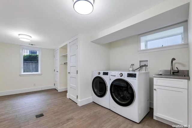 clothes washing area featuring cabinets, separate washer and dryer, light hardwood / wood-style floors, and sink