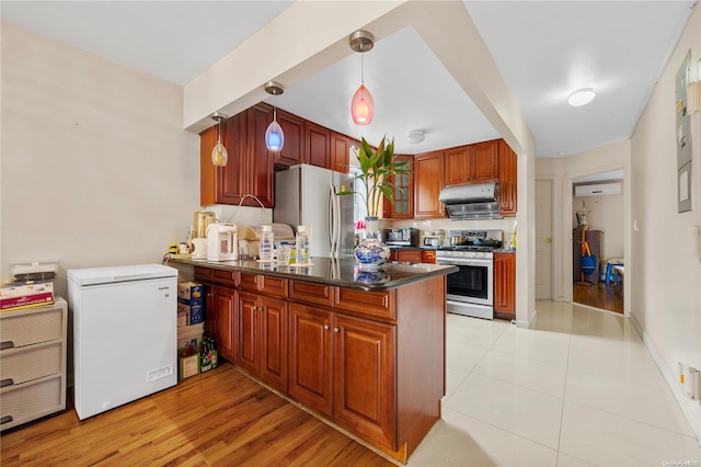 kitchen featuring hanging light fixtures, stainless steel appliances, kitchen peninsula, light hardwood / wood-style floors, and decorative backsplash