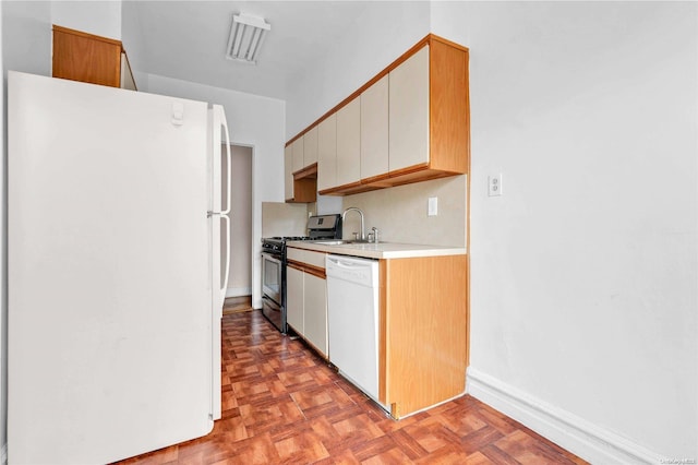 kitchen with white cabinets, white appliances, sink, and light parquet flooring