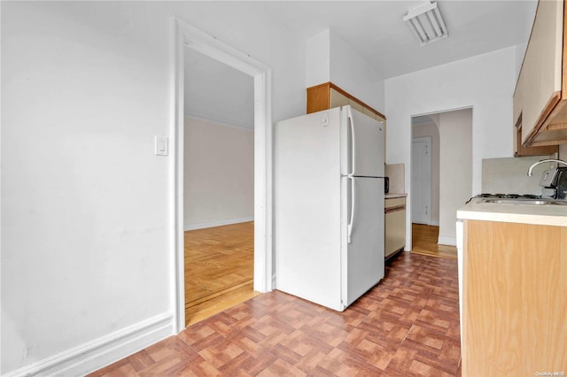 kitchen with white refrigerator, sink, and light parquet floors