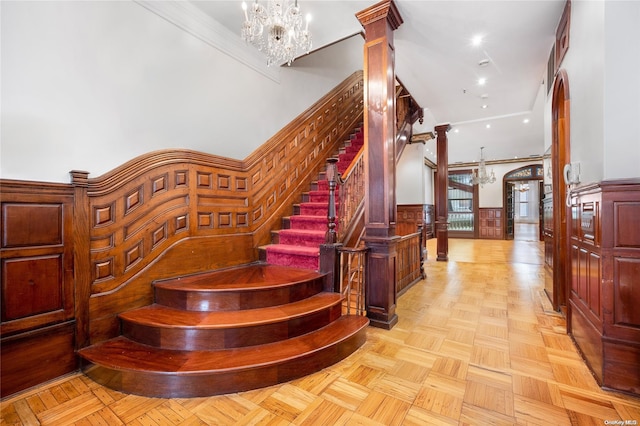 stairs with a towering ceiling, decorative columns, and parquet floors