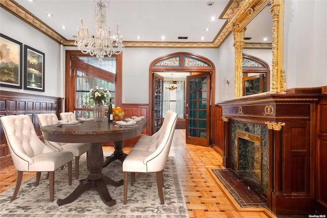 dining room with a high end fireplace, an inviting chandelier, light parquet flooring, and ornamental molding