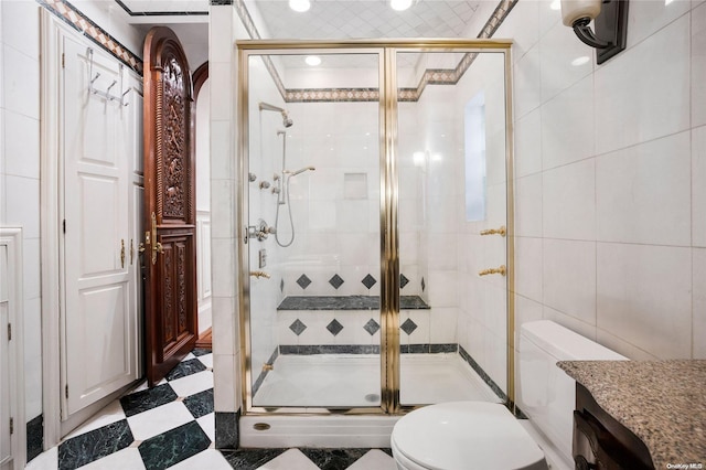 bathroom featuring vanity, a shower with door, crown molding, toilet, and tile walls