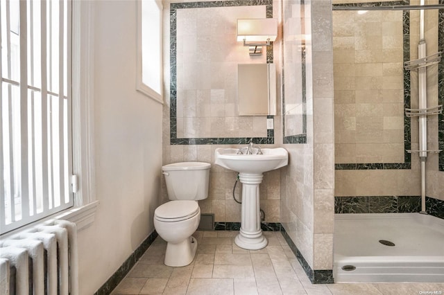 bathroom featuring radiator, tile patterned flooring, toilet, tiled shower, and tile walls