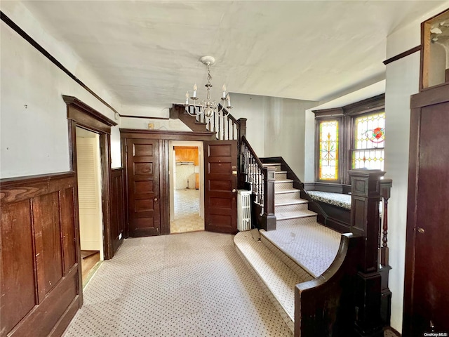 carpeted entryway with a chandelier