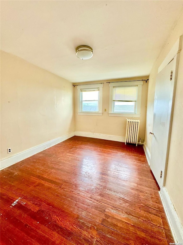 empty room with radiator heating unit and hardwood / wood-style flooring