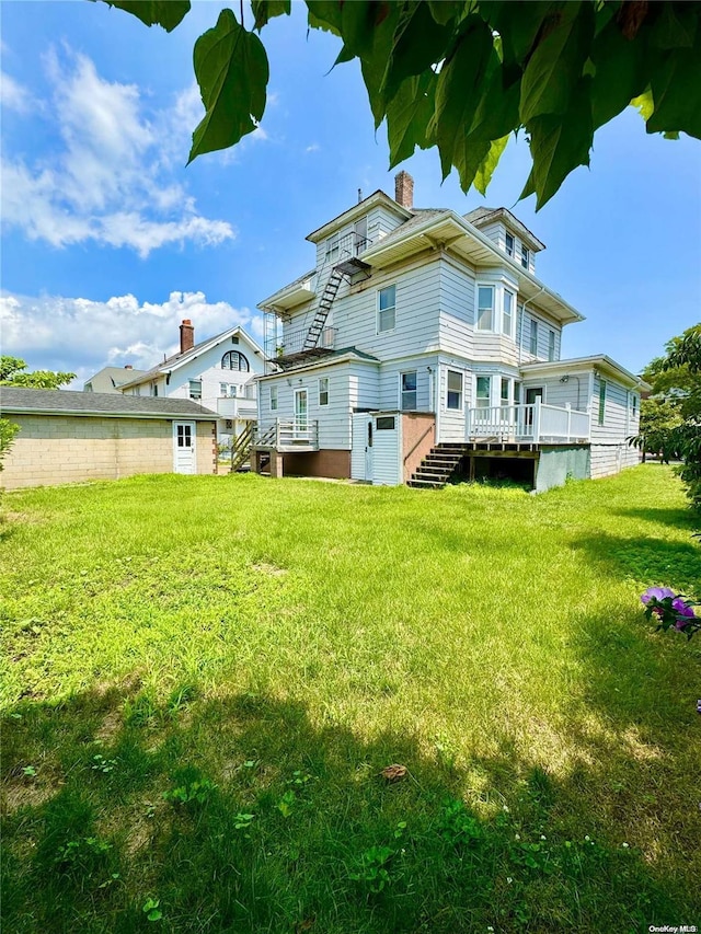 back of property featuring a lawn and a deck