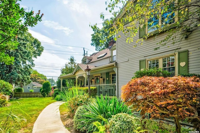 view of side of home with covered porch and a yard