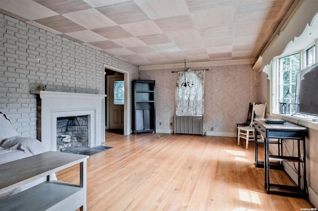 living room with light wood-type flooring, radiator, a notable chandelier, and brick wall