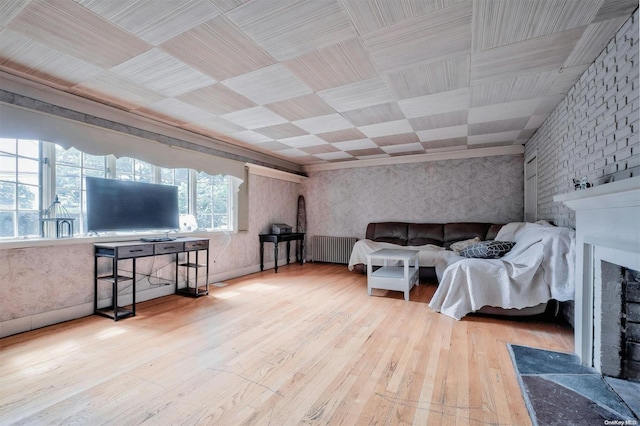 bedroom with a large fireplace, radiator, and light hardwood / wood-style flooring