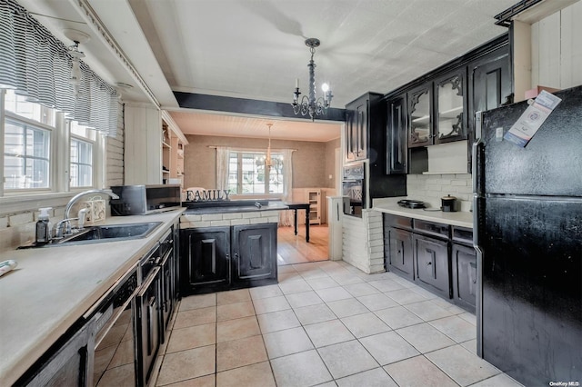 kitchen with black refrigerator, light tile patterned floors, an inviting chandelier, and hanging light fixtures