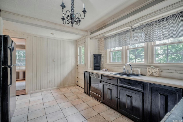 kitchen featuring black appliances, sink, wooden walls, light tile patterned floors, and radiator heating unit