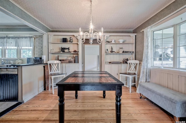 dining room featuring a wealth of natural light, light hardwood / wood-style flooring, crown molding, and an inviting chandelier