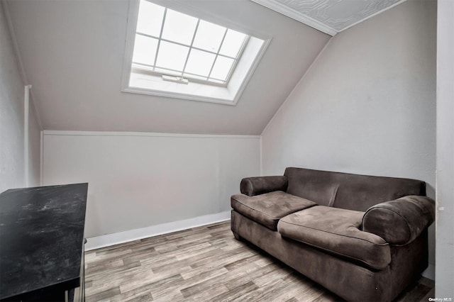 living area featuring light hardwood / wood-style floors, crown molding, and lofted ceiling