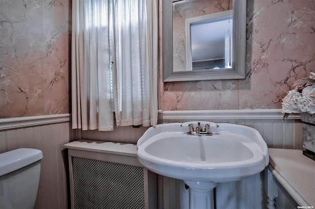 bathroom featuring wood walls, sink, and toilet