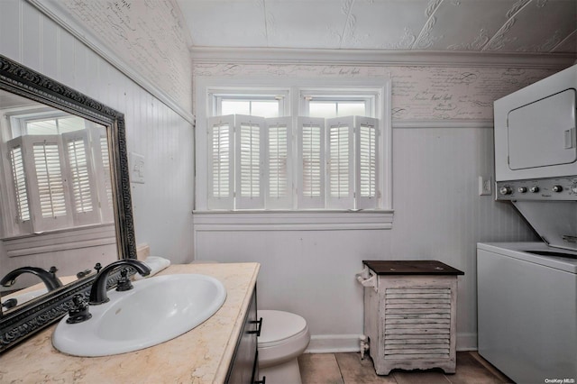 bathroom featuring vanity, stacked washer and clothes dryer, tile patterned floors, wooden walls, and toilet