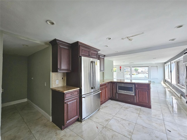 kitchen with kitchen peninsula, appliances with stainless steel finishes, and tasteful backsplash