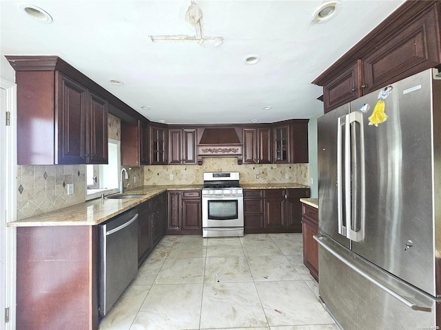 kitchen featuring sink, decorative backsplash, light stone countertops, appliances with stainless steel finishes, and custom range hood