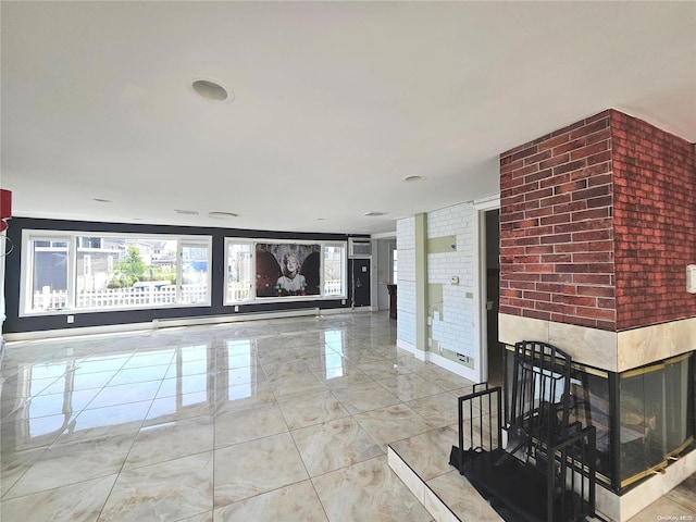 interior space with a multi sided fireplace, brick wall, and a baseboard radiator