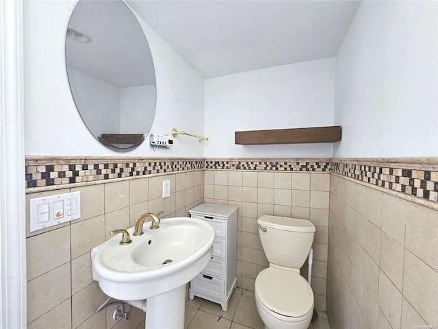 bathroom featuring tile patterned flooring, toilet, tile walls, and sink