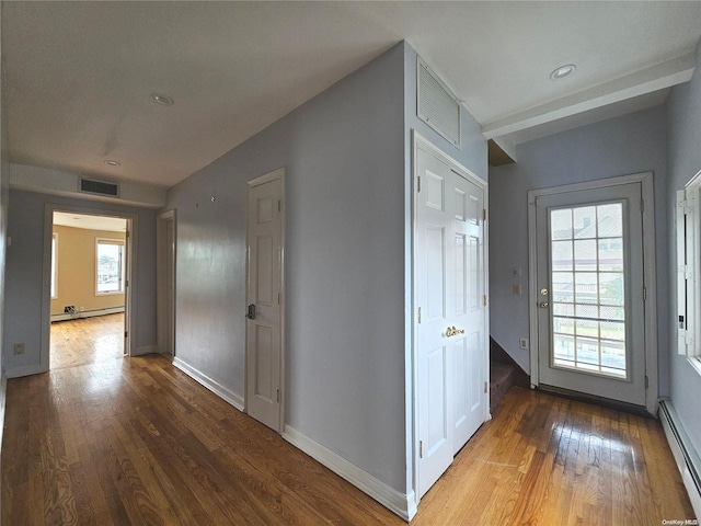 corridor with wood-type flooring and baseboard heating