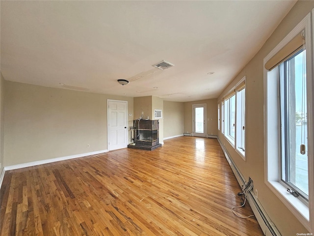 unfurnished living room featuring a multi sided fireplace, light wood-type flooring, and baseboard heating