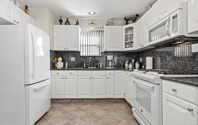 kitchen with decorative backsplash, white appliances, sink, dark stone countertops, and white cabinets