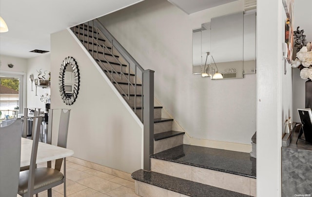 stairway featuring tile patterned flooring and an inviting chandelier