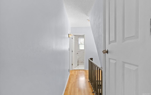 hallway with light hardwood / wood-style floors and a textured ceiling