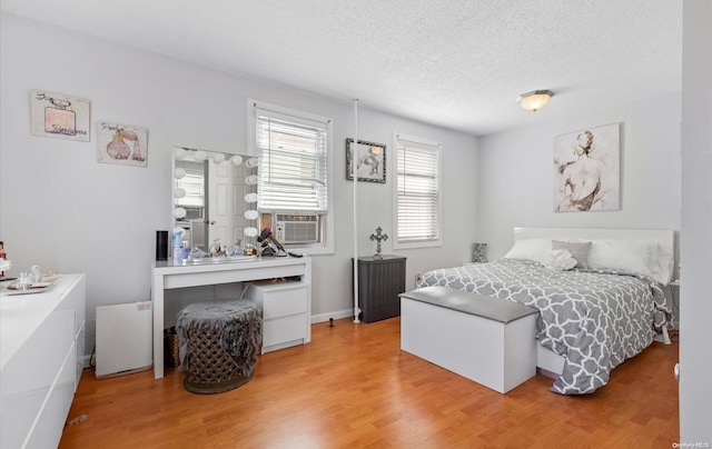 bedroom featuring radiator heating unit, cooling unit, wood-type flooring, and a textured ceiling