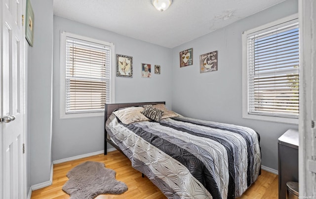 bedroom featuring a textured ceiling and light hardwood / wood-style flooring