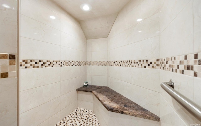 bathroom with tiled shower, tile walls, and lofted ceiling