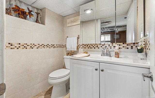 bathroom with vanity, backsplash, tile patterned flooring, toilet, and tile walls