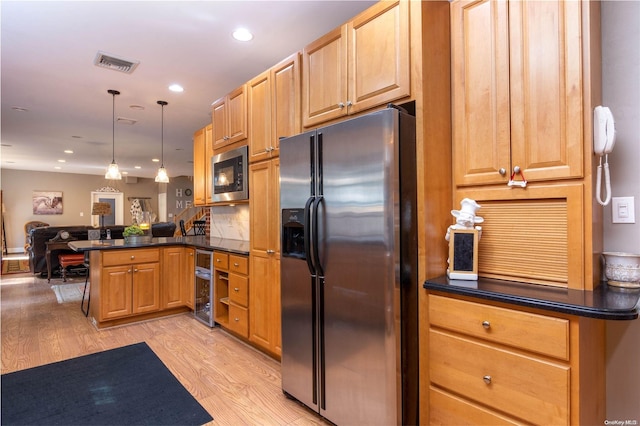 kitchen with kitchen peninsula, stainless steel appliances, hanging light fixtures, and light hardwood / wood-style flooring