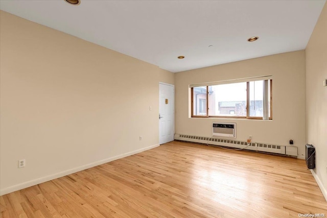 spare room with baseboard heating and light hardwood / wood-style flooring