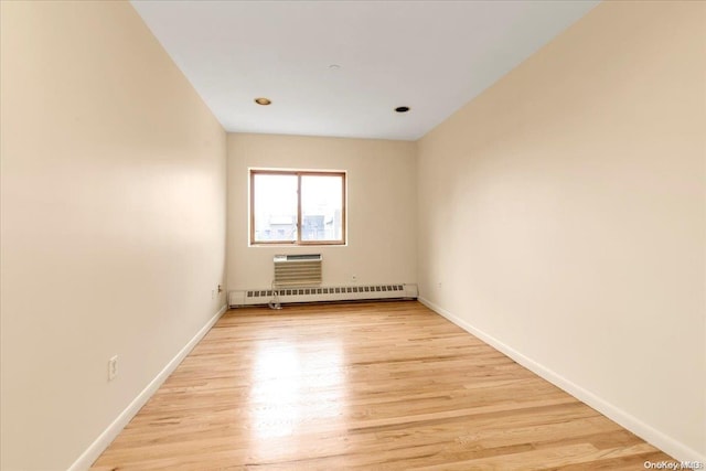 spare room with an AC wall unit, light hardwood / wood-style flooring, and a baseboard heating unit