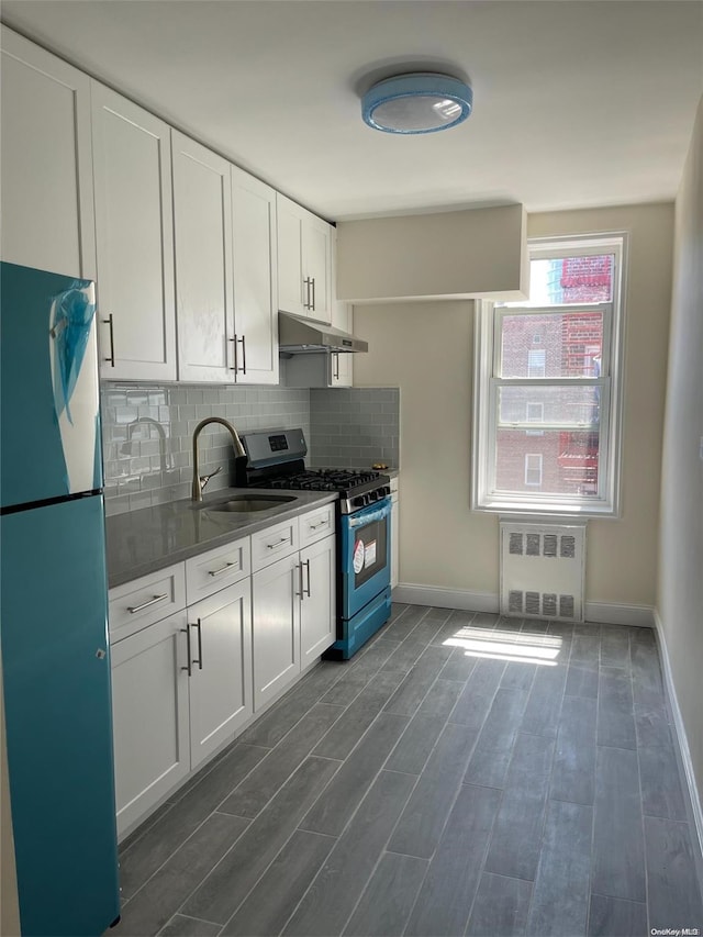 kitchen featuring radiator, white cabinets, refrigerator, sink, and stainless steel range with gas stovetop