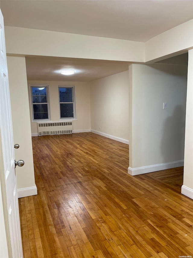 unfurnished room with hardwood / wood-style floors and radiator heating unit