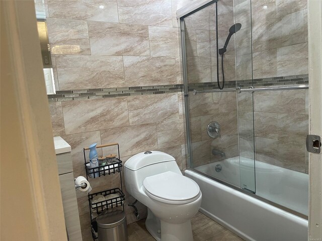 bathroom with bath / shower combo with glass door and toilet