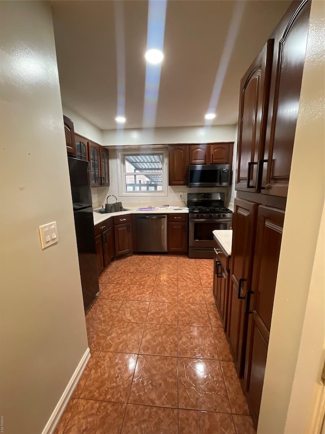 kitchen with sink, light tile patterned floors, appliances with stainless steel finishes, tasteful backsplash, and dark brown cabinets