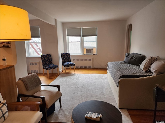 living room featuring radiator heating unit, cooling unit, and light hardwood / wood-style floors