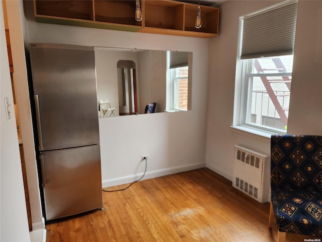 kitchen with stainless steel refrigerator, radiator heating unit, and hardwood / wood-style floors