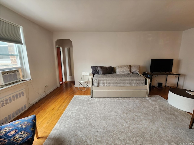 bedroom with hardwood / wood-style flooring, cooling unit, and radiator heating unit