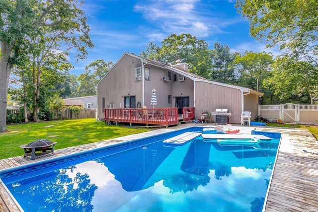 view of pool with a lawn, area for grilling, a fire pit, and a deck