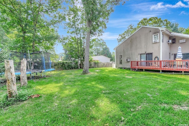 view of yard with a trampoline, a deck, and an AC wall unit