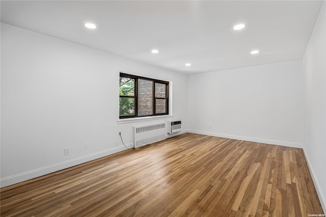 spare room featuring wood-type flooring, heating unit, and radiator