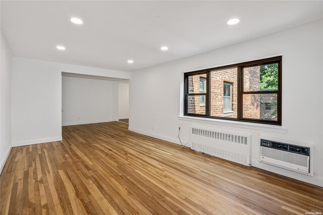 spare room with radiator, light hardwood / wood-style flooring, and a wall mounted AC