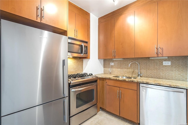 kitchen featuring light stone countertops, tasteful backsplash, stainless steel appliances, sink, and light tile patterned flooring