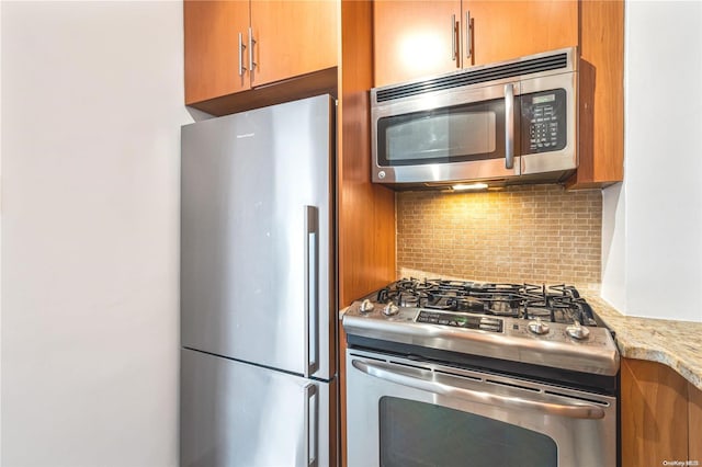 kitchen with light stone countertops, stainless steel appliances, and tasteful backsplash